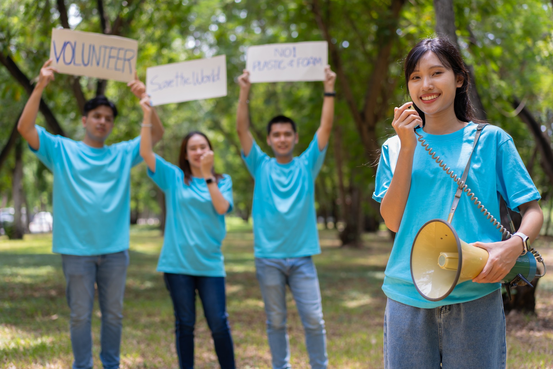 Happy young Asian students diverse volunteers hold a campaign sign for cleaning in the park, The concept of environmental conservation on world environment day, recycling, charity for sustainability.