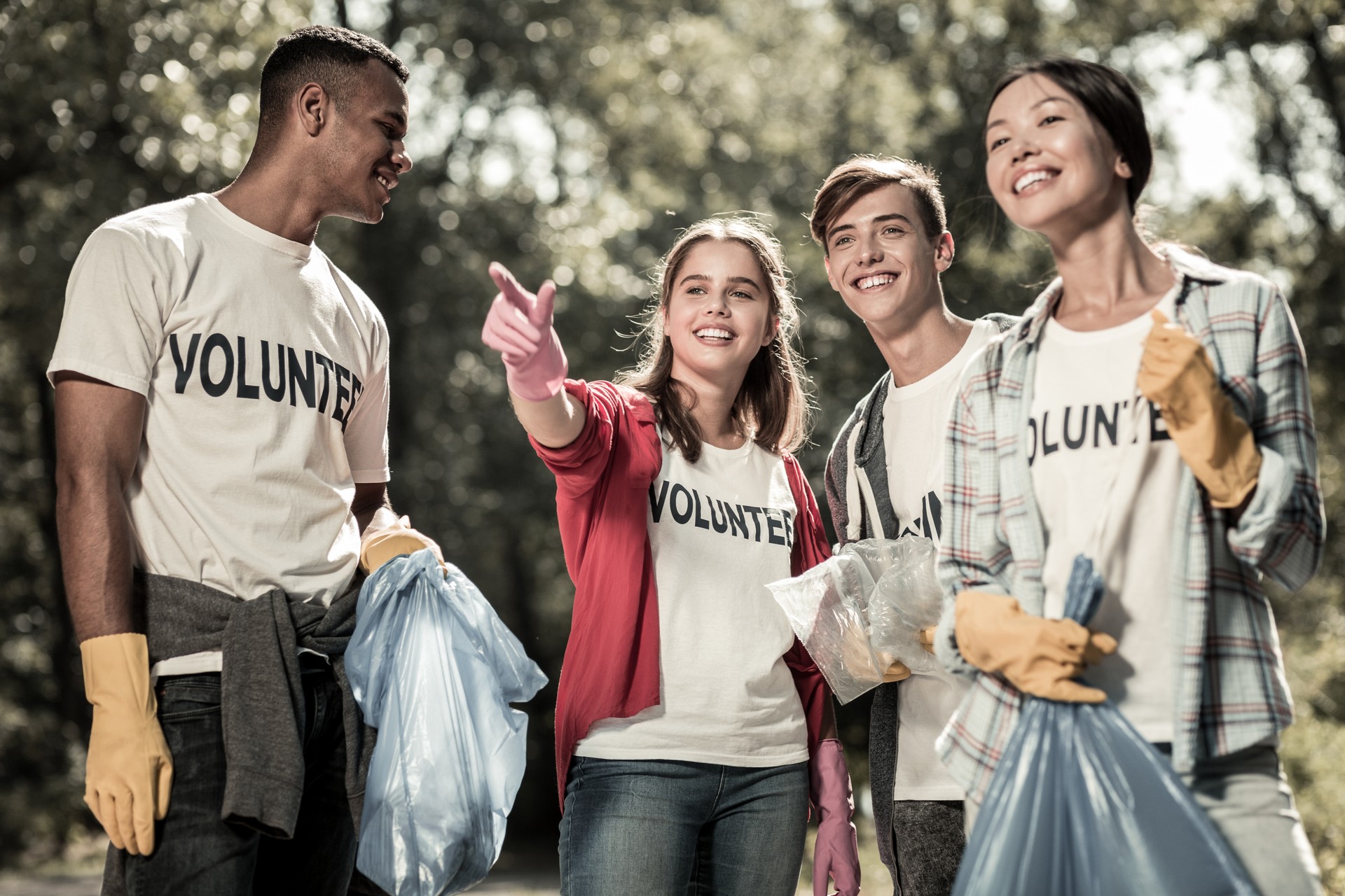 Smiling young pupils feeling involved in cleaning up the forest and volunteering